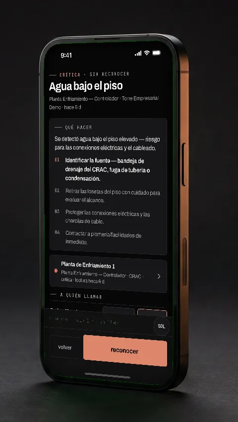 La app Vaultis en un teléfono: alarma «Agua bajo el piso» con su bloque «qué hacer» en cuatro pasos.